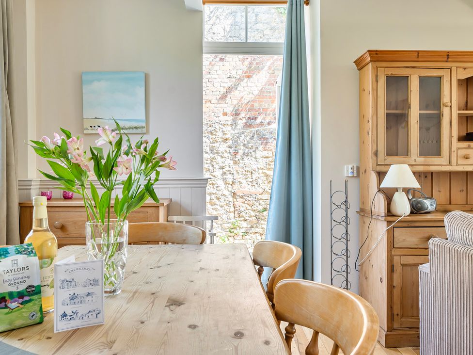 A dining room with a wooden table and flowers at East Wing in Crewkerne