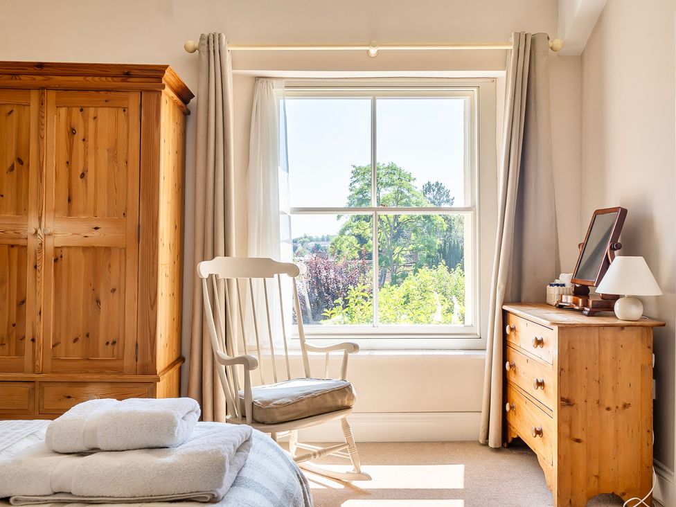 A bedroom with a wardrobe and a window at East Wing in Crewkerne