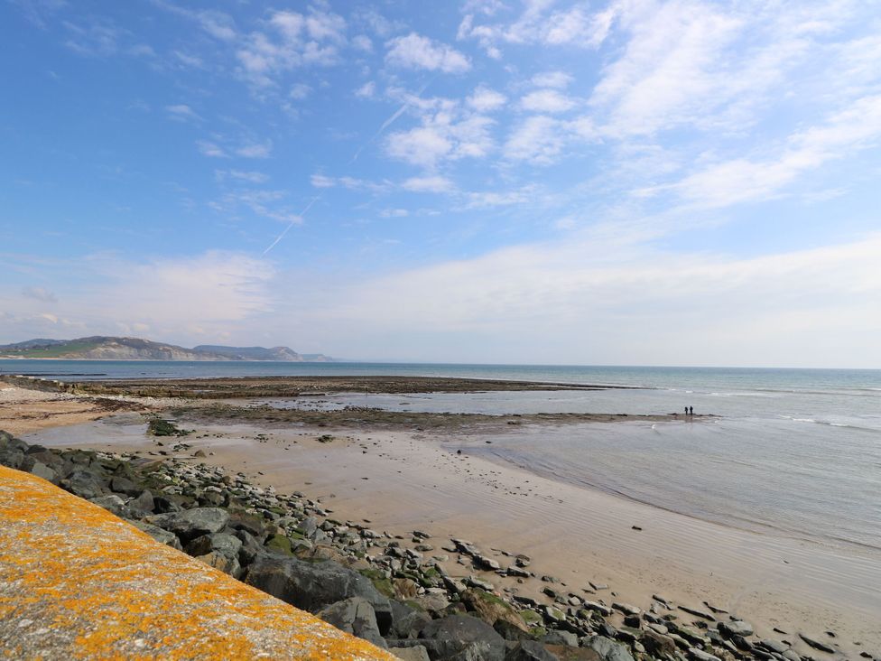 A beach with a rocky shore and people walking at East Wing in Crewkerne
