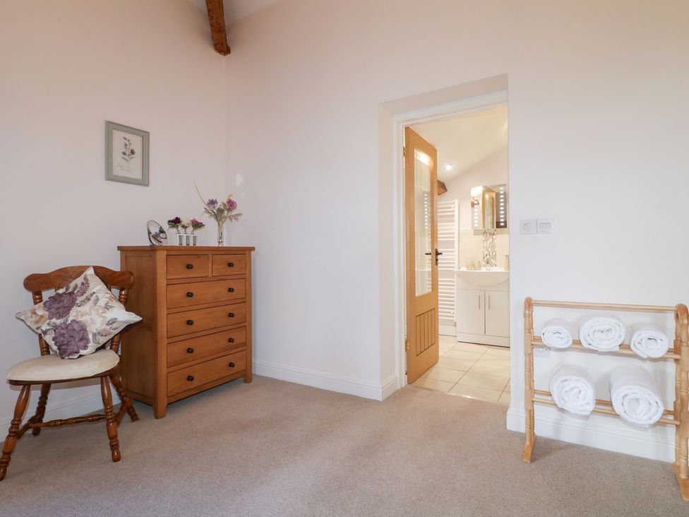 A bedroom with a chair, a dresser, and towels at The Dairy in Eastwood