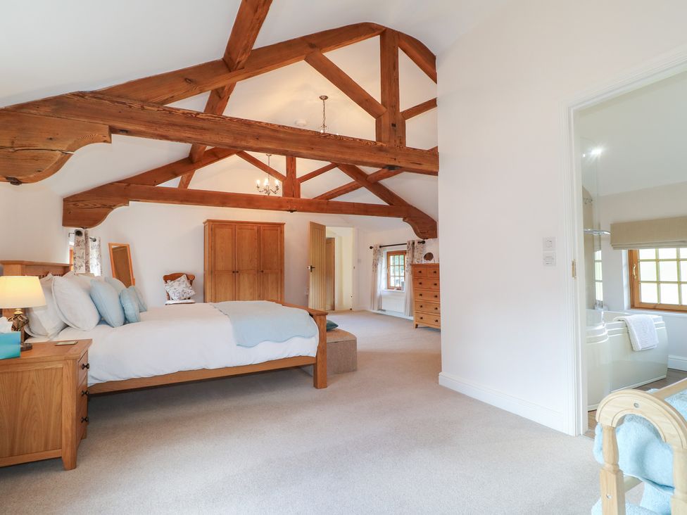 A bedroom with a bed and wooden furniture at The Dairy in Eastwood