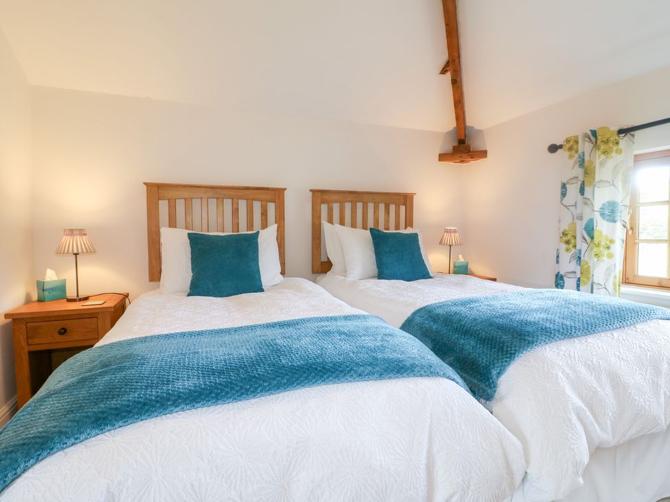 A bedroom with two beds and bedside tables at The Dairy in Eastwood