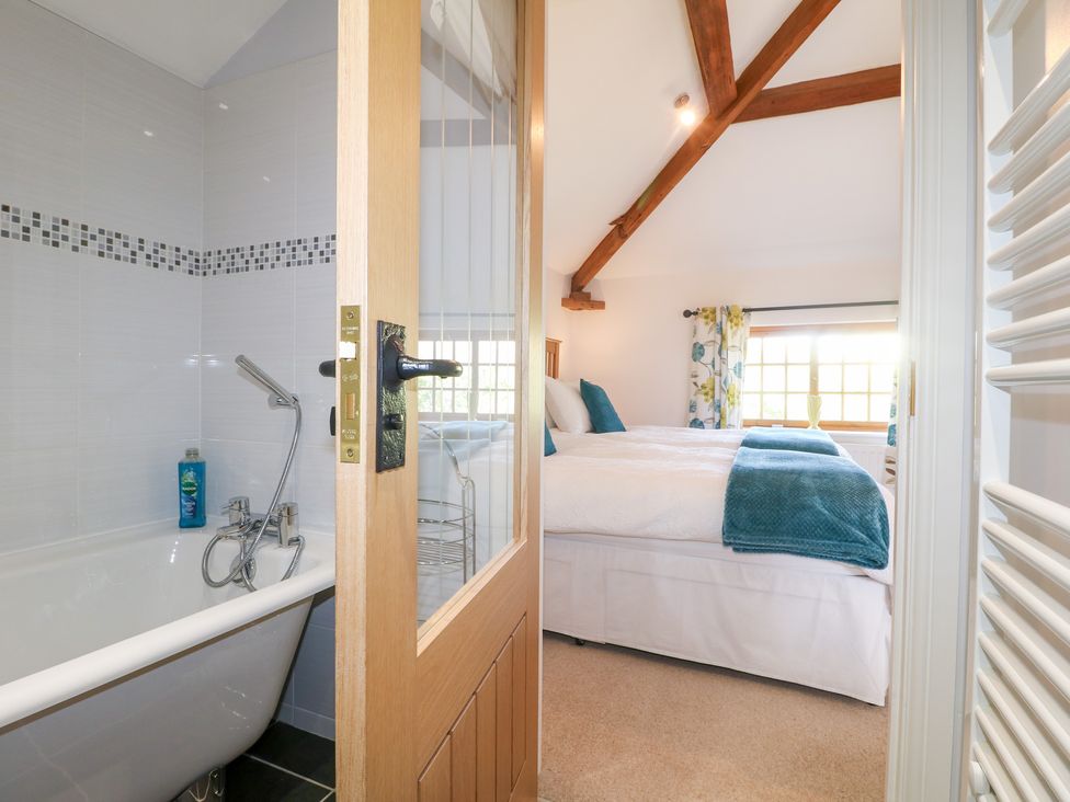 A bathroom with a bathtub and a bed visible in the adjoining room at The Dairy Eastwood