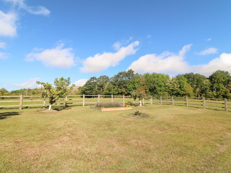 A garden with a flower bed and trees at The Dairy in Eastwood