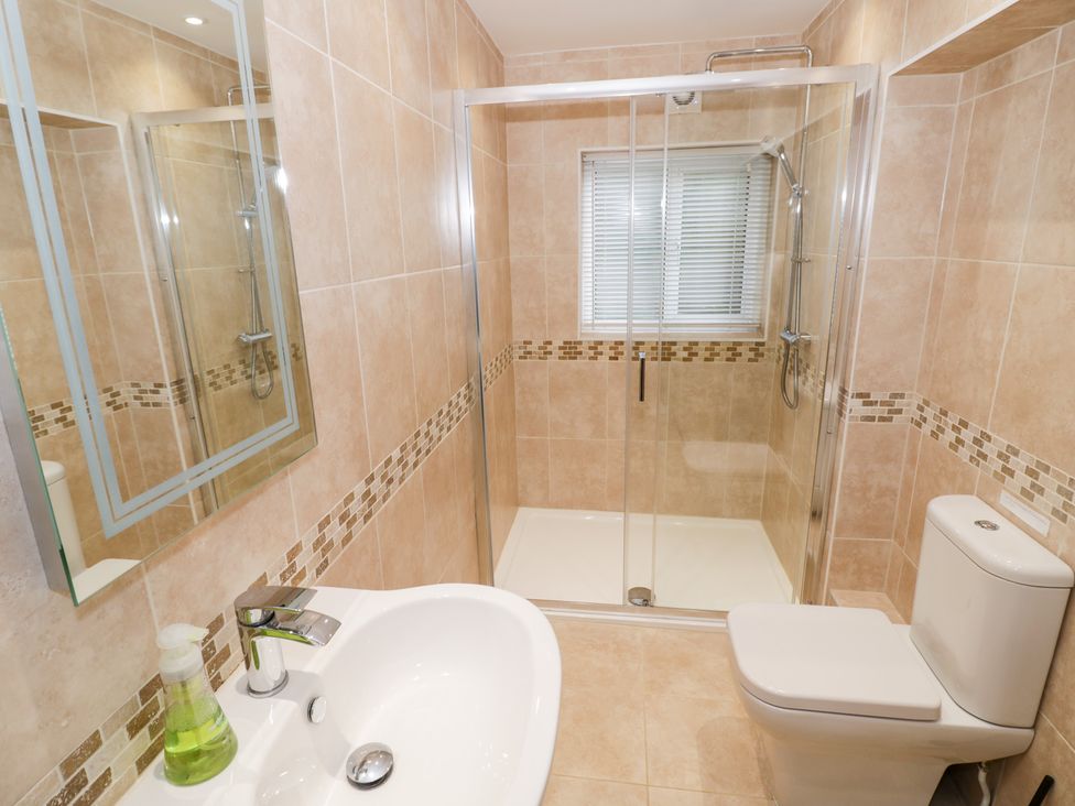 A bathroom with a shower, sink, toilet, and a mirror at Town Mill in Bewdley