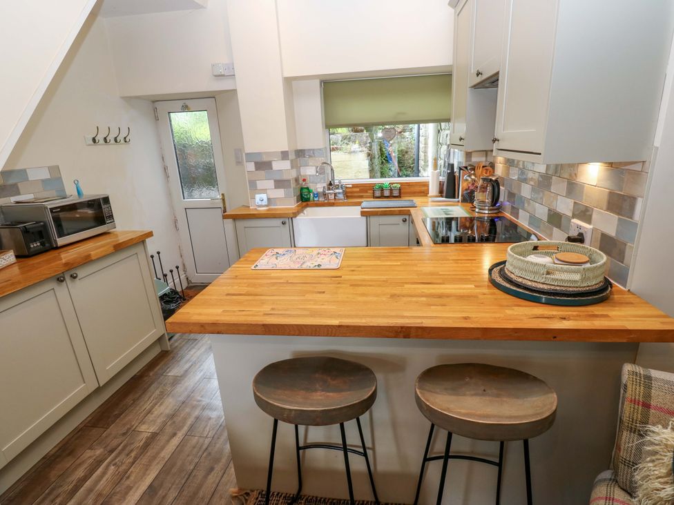 A kitchen with countertop, sink, and stools at Maria Cottage in Haworth