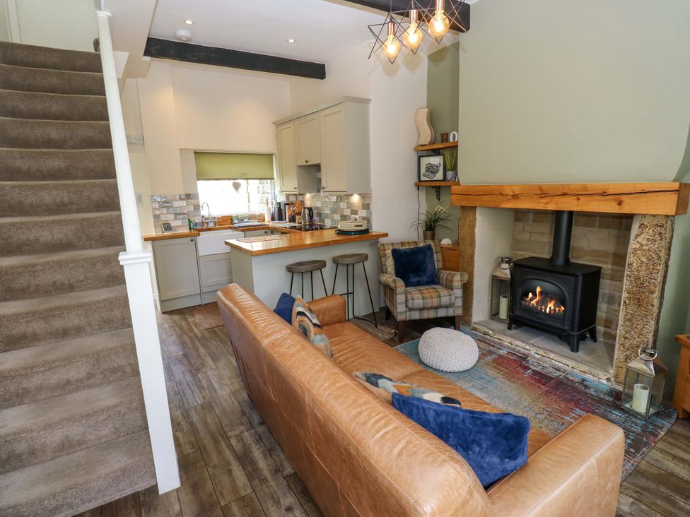 A living room with a sofa and fireplace at Maria Cottage in Haworth