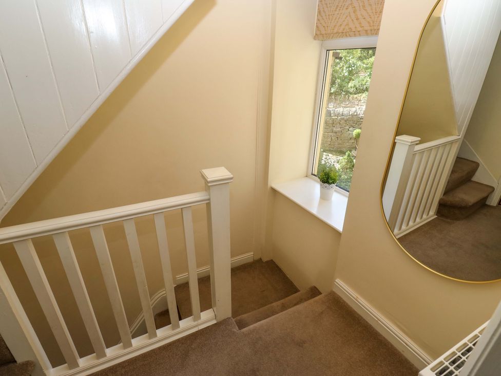 A hallway with stairs and a window at Maria Cottage in Haworth