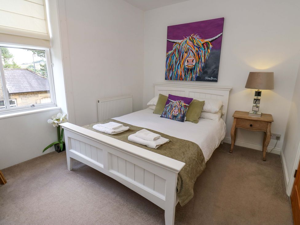 A bedroom with a bed, lamp and artwork at Maria Cottage, Haworth
