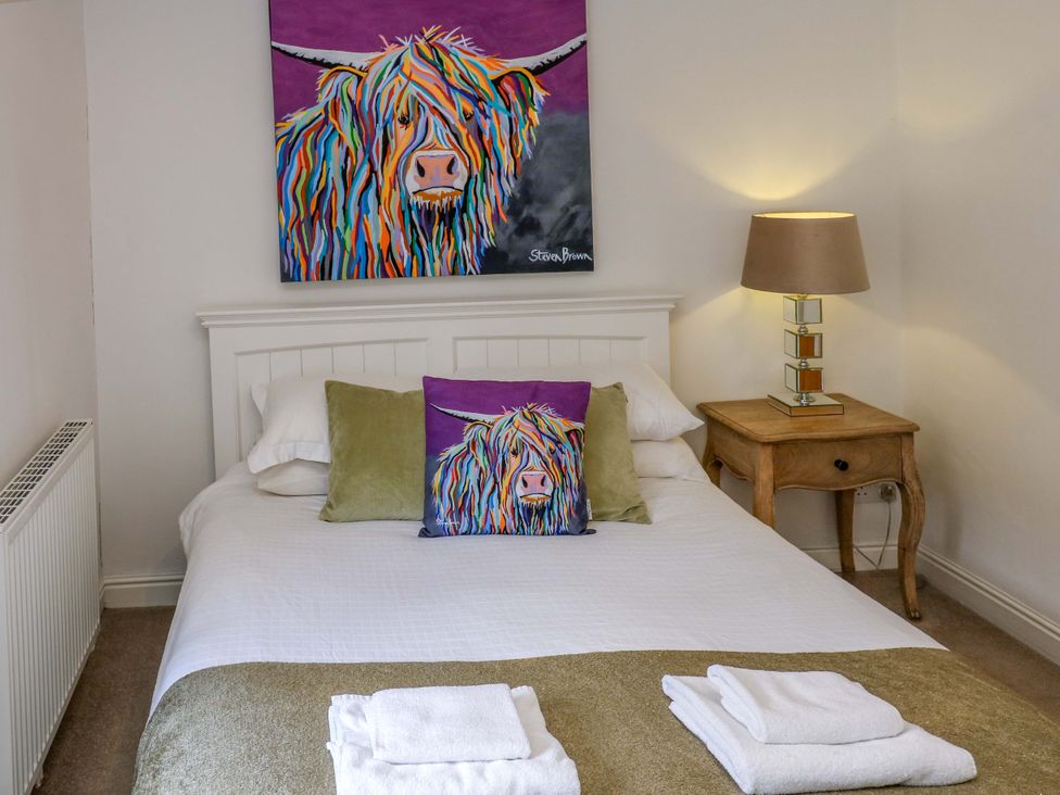 A bedroom with a bed and artwork at Maria Cottage in Haworth