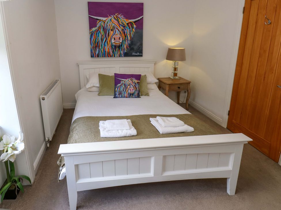 A bedroom with a bed and a painting at Maria Cottage in Haworth