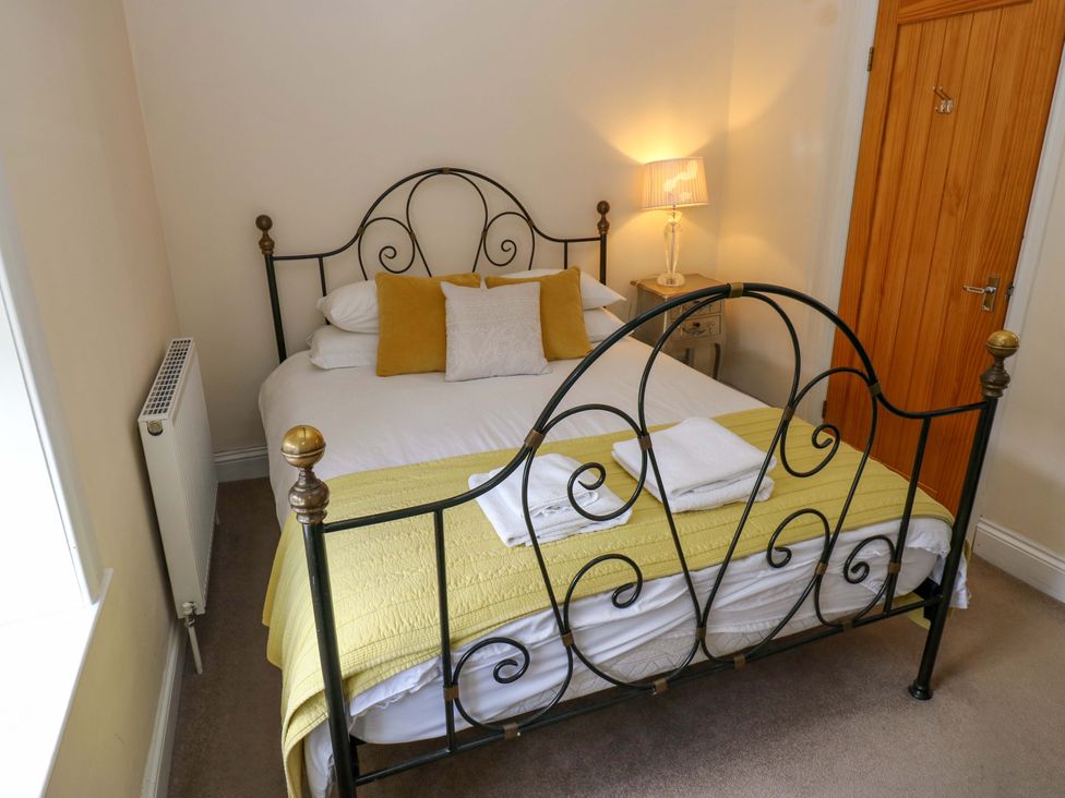 A bedroom with a bed, nightstand, and lamp at Maria Cottage in Haworth