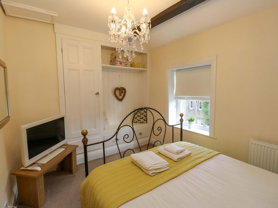A bedroom with a bed and a television at Maria Cottage in Haworth