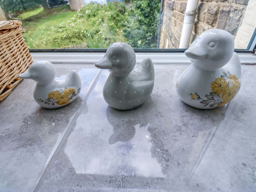 Three ceramic ducks and a basket on a windowsill at Maria Cottage in Haworth