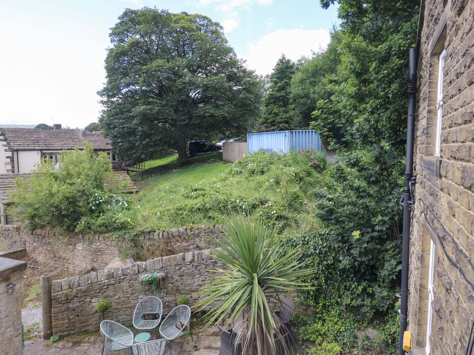 A garden with a tree and seating area at Maria Cottage in Haworth