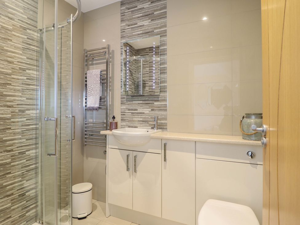 A bathroom with a shower, wash basin, and toilet at Moelfre Cottage in Llanbedr