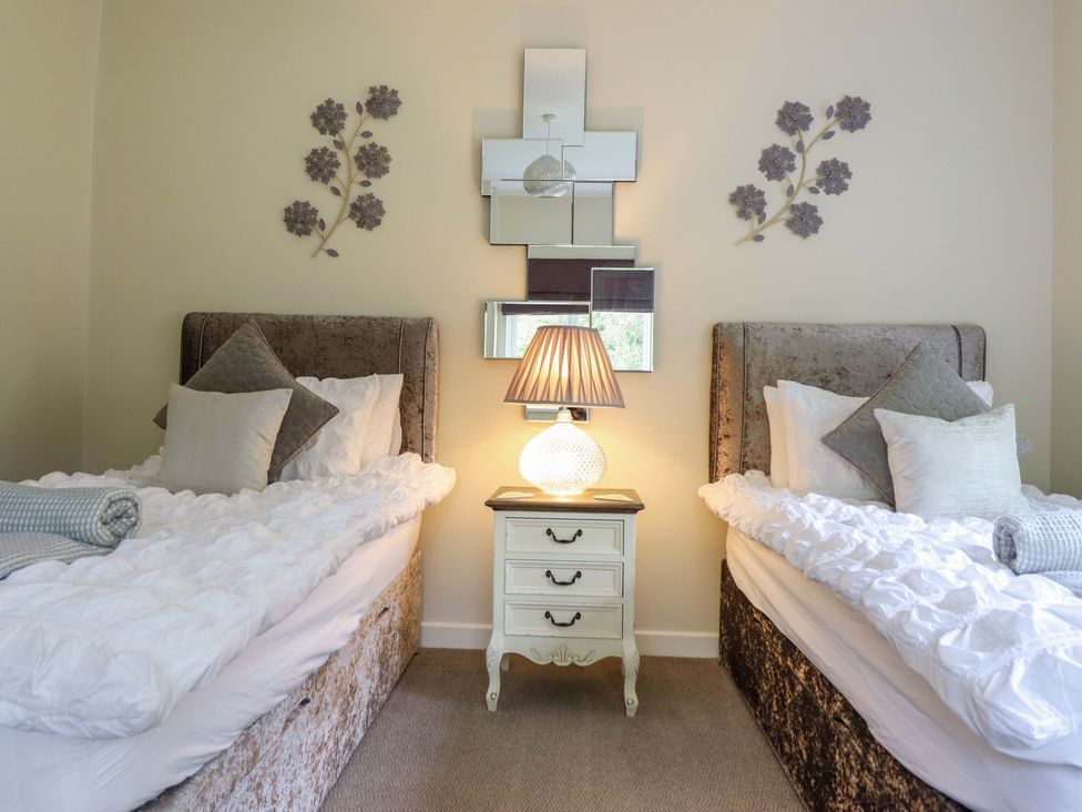 A bedroom with two beds and a nightstand at Moelfre Cottage Llanbedr
