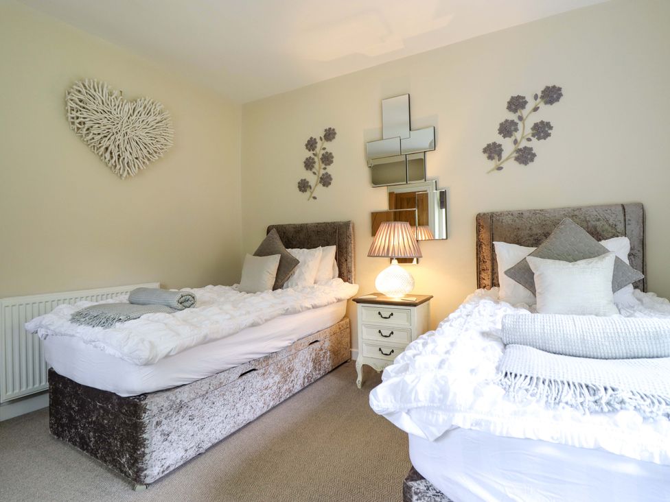 A bedroom with two beds and a lamp on a bedside table at Moelfre Cottage Llanbedr