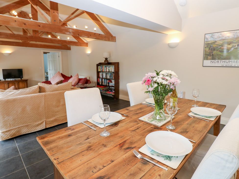 An open plan living and dining area with a dining table and sofa at Gallow Law Cottage in Bellingham