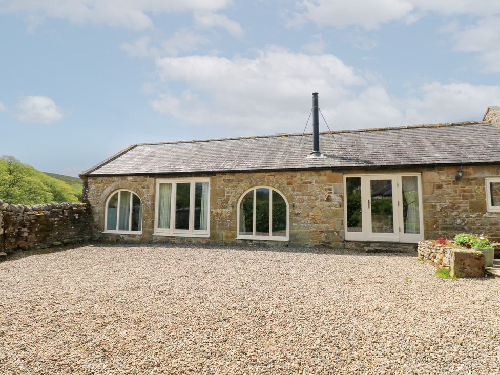 An exterior view of a cottage with stone walls and windows at Gallow Law Cottage in Bellingham