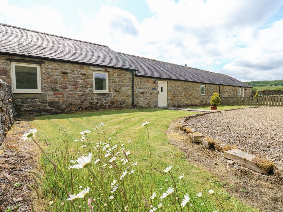 A stone building with windows and grass at Shepherds Burn Cottage in Bellingham