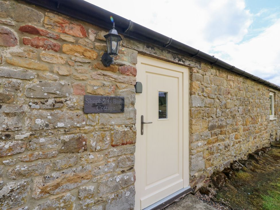 An entrance with stone wall and door at Shepherds Burn Cottage in Bellingham