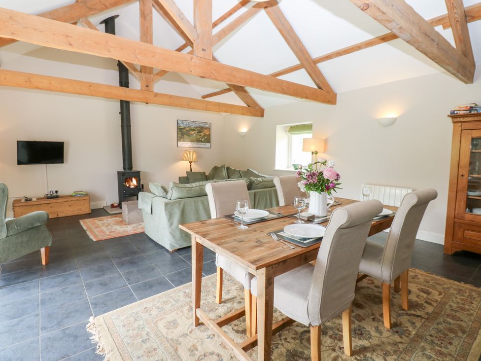 A living room with a dining area and wood stove at Shepherds Burn Cottage in Bellingham
