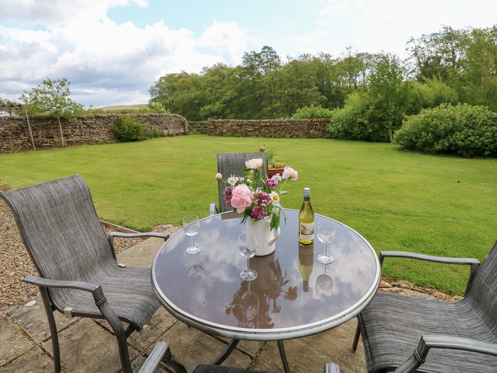 A table with chairs and flowers in a garden at Shepherds Burn Cottage Bellingham