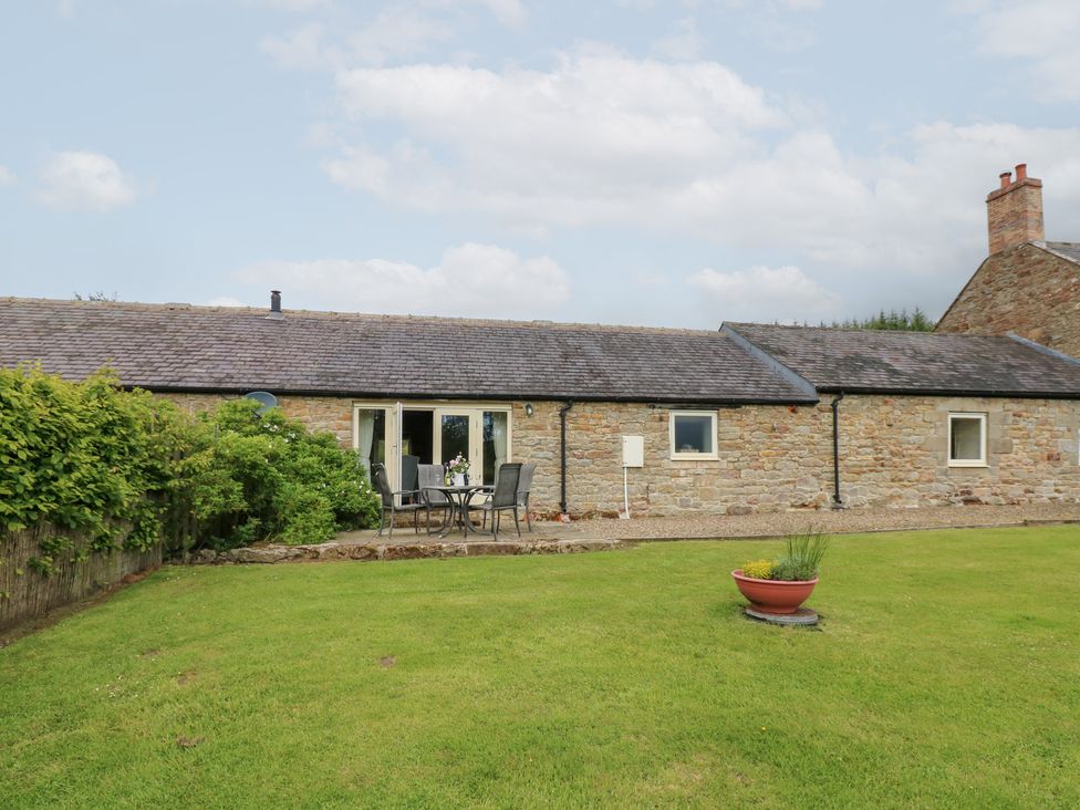 A cottage with seating area and garden at Shepherds Burn Cottage in Bellingham