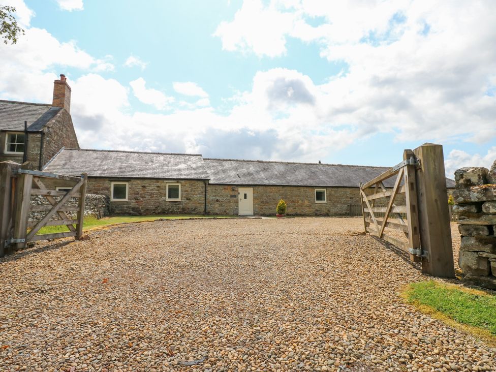 An outdoor area with a gravel driveway and a stone building at Shepherds Burn Cottage Bellingham