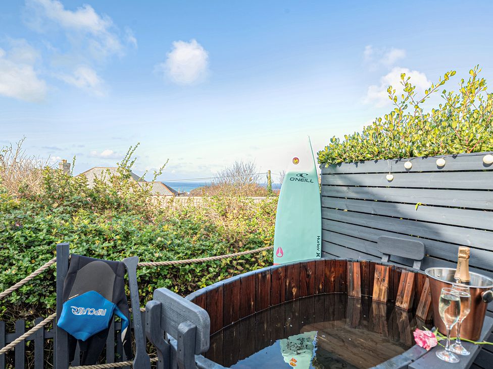 An outdoor area with a hot tub and surfboard at Sunset View in Porth