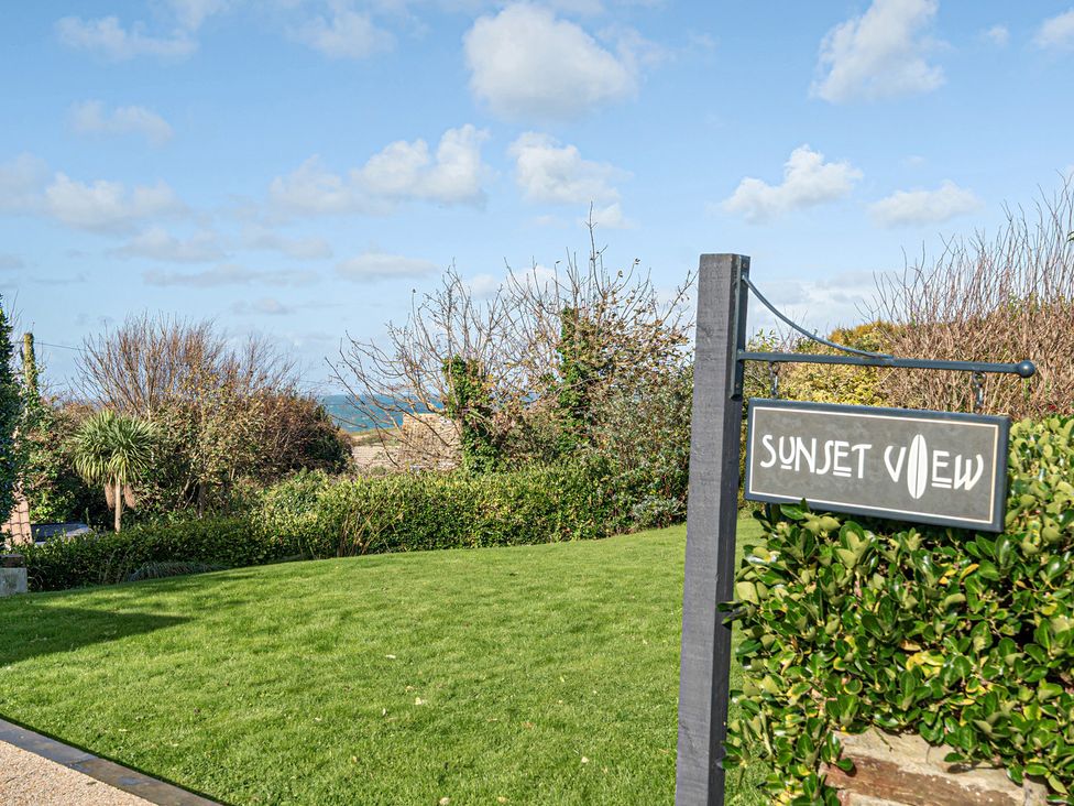A sign for Sunset View near grass and trees in Porth