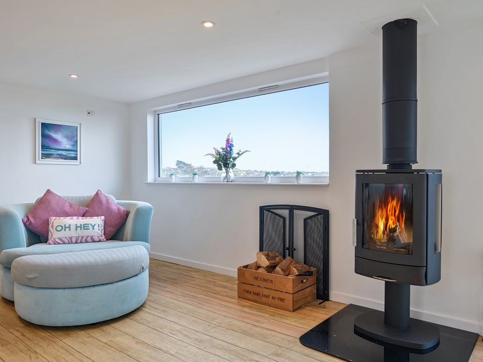 A living room with a fireplace and armchair at Sunset View in Porth