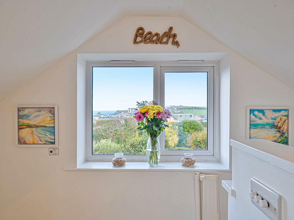A window with flowers and artwork at Sunset View in Porth