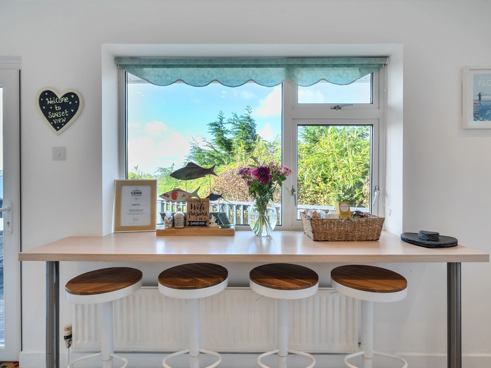 A kitchen with a bar table and flowers at Sunset View in Porth