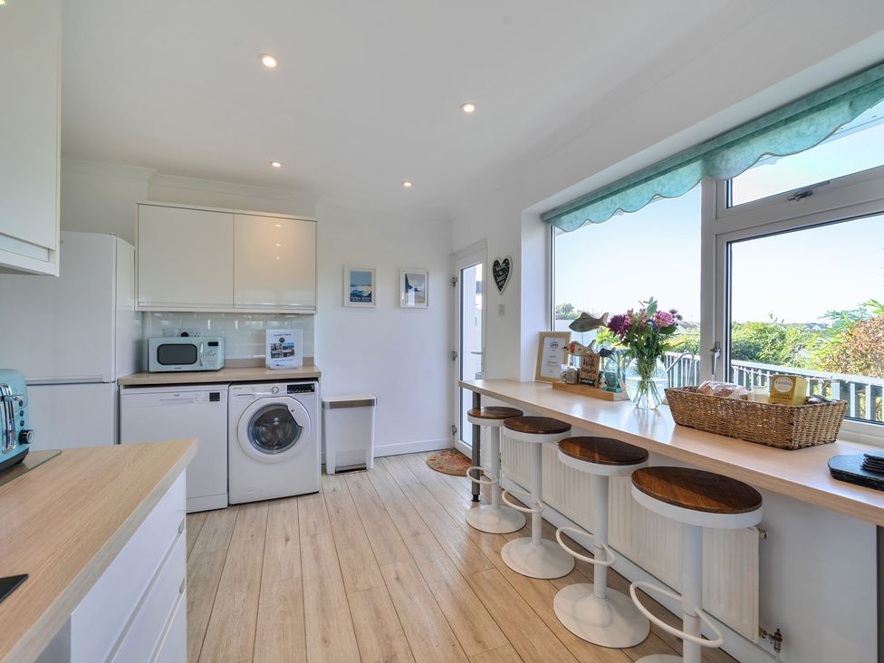 A kitchen with appliances and bar seating at Sunset View in Porth