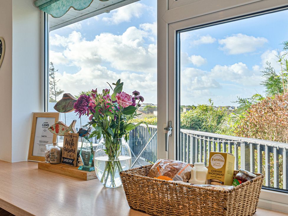 A kitchen with a window displaying flowers and a basket at Sunset View in Porth
