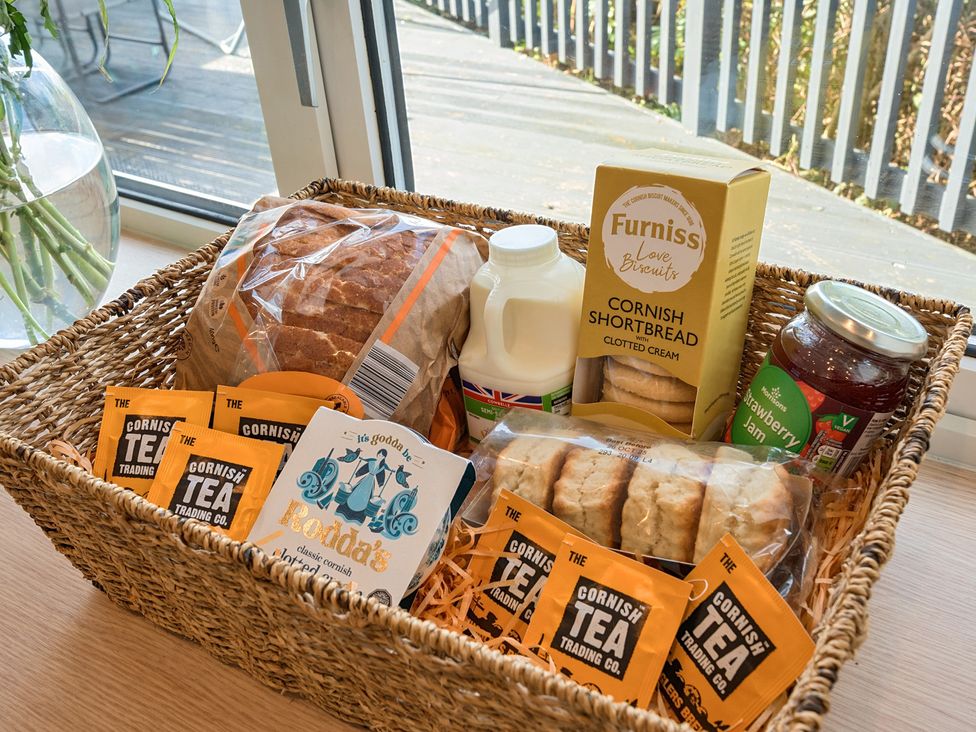 A basket containing bread, milk, shortbread, strawberry jam, and tea bags at Sunset View in Porth