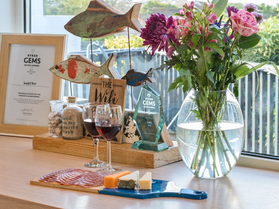 A table with wine glasses, cheese, and flowers at Sunset View in Porth