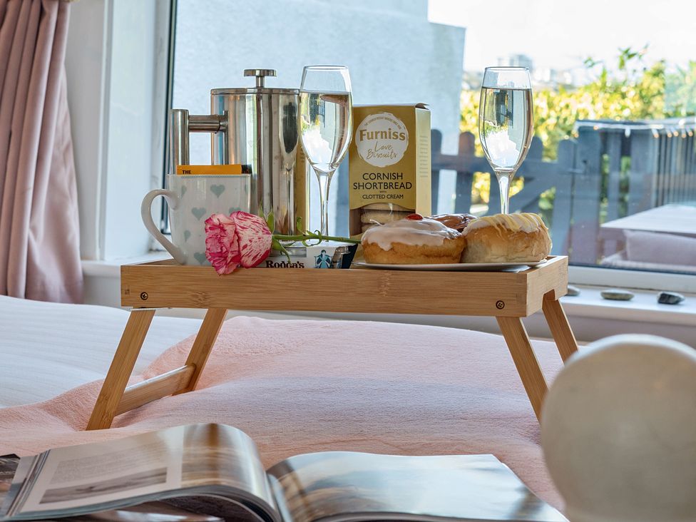 A breakfast tray with drinks and snacks on a bed at Sunset View in Porth