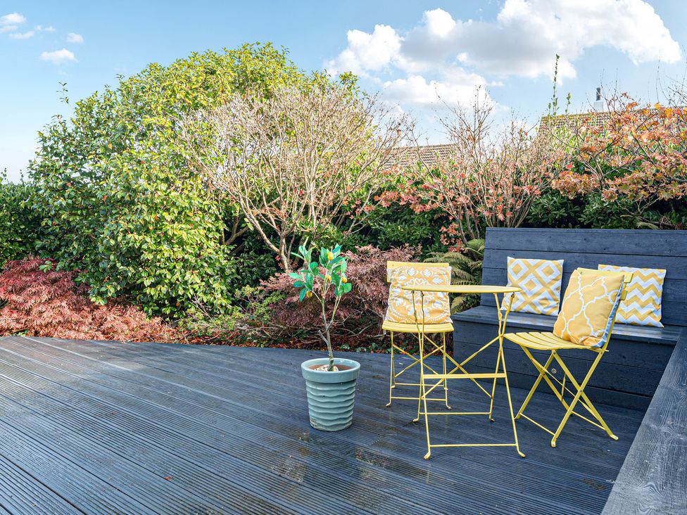 A garden with a table and chairs on a deck at Sunset View in Porth