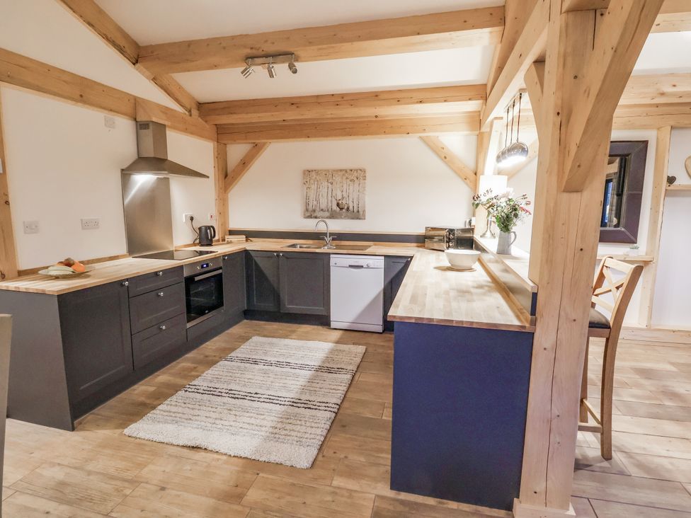 A kitchen with wooden beams and appliances at Lady Bagots Cabin in Ruthin