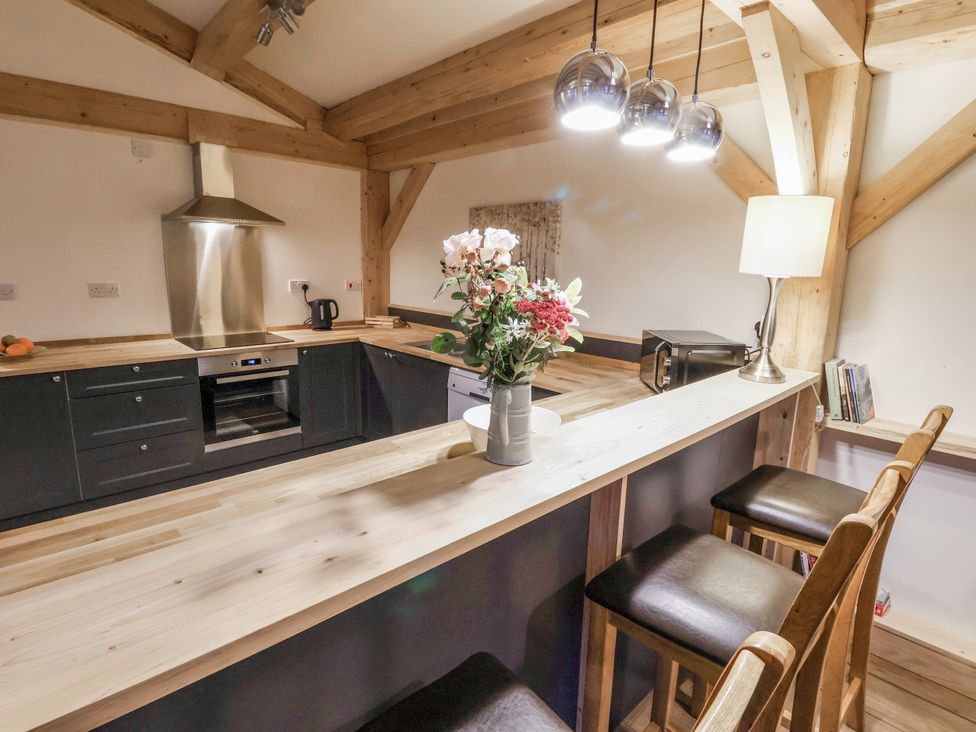 A kitchen with a bar counter and stools at Lady Bagots Cabin in Ruthin