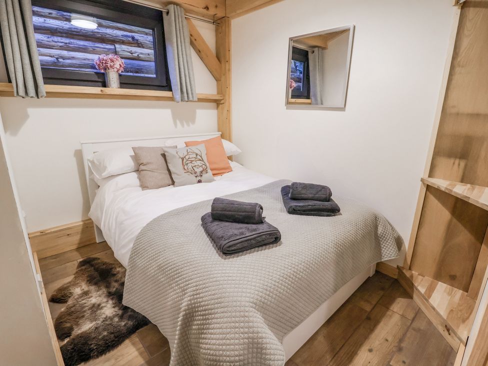 A bedroom with a bed and towels on top at Lady Bagots Cabin in Ruthin