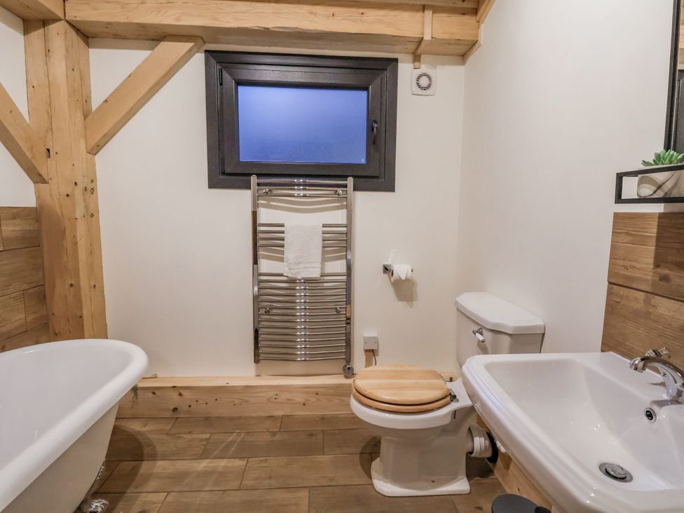 A bathroom with bathtub, toilet, towel rack, and sink at Lady Bagots Cabin in Ruthin