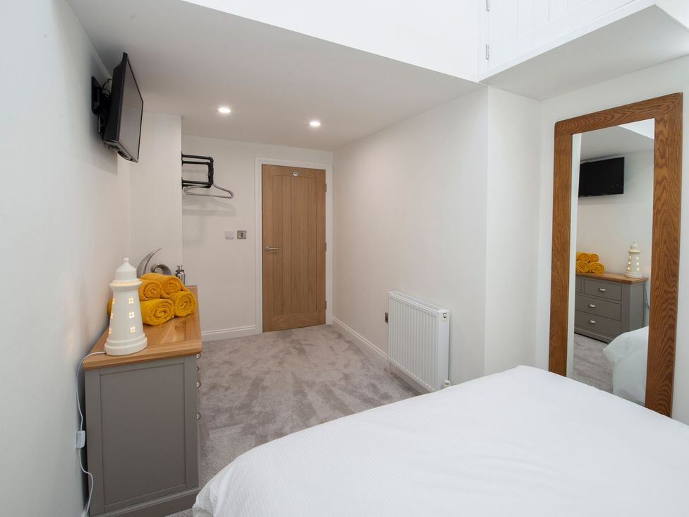 A bedroom with a television, towels, and a dresser at Harbour Sunset