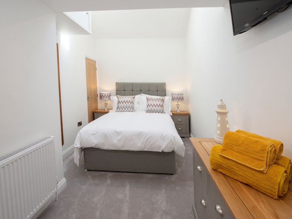 A bedroom with a bed, bedside tables, and a dresser at Harbour Sunset