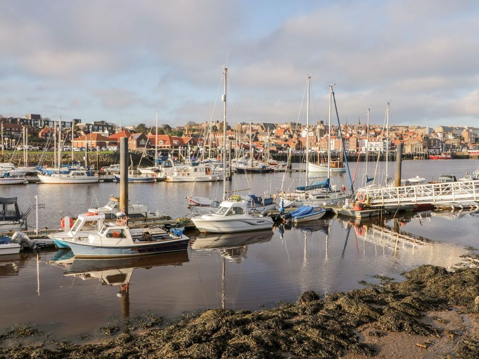 A marina with boats and buildings reflected in the water at Harbour Sunset