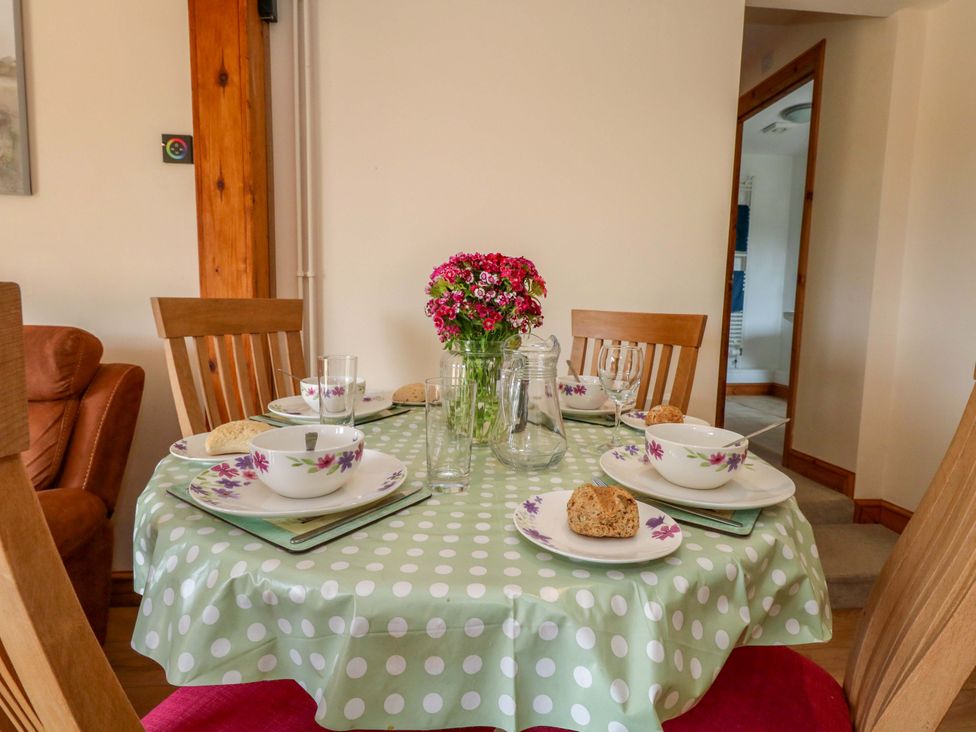 A dining room table set with dishes and flowers at Mallows Byre in Yetminster