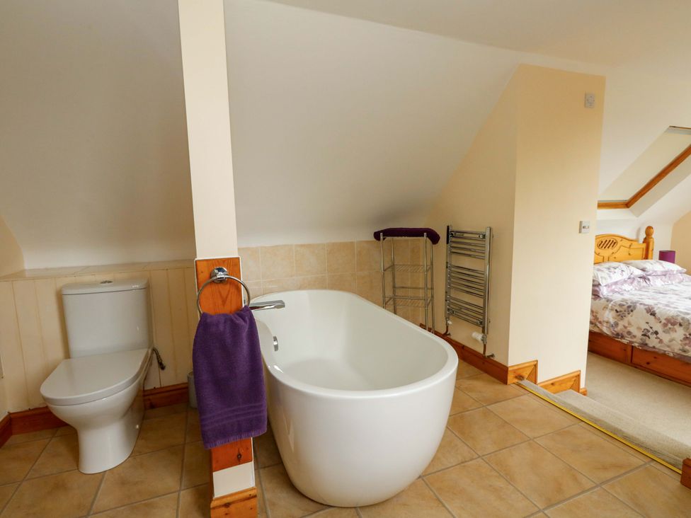 A bathroom with a bathtub and toilet at Mallows Byre in Yetminster